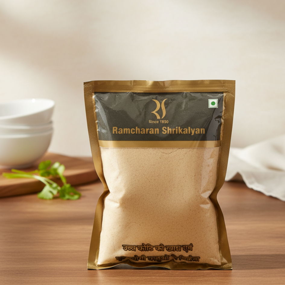 Packaged product from Ramcharan Shrikalyan on a wooden surface with bowls and green leaves in the background.